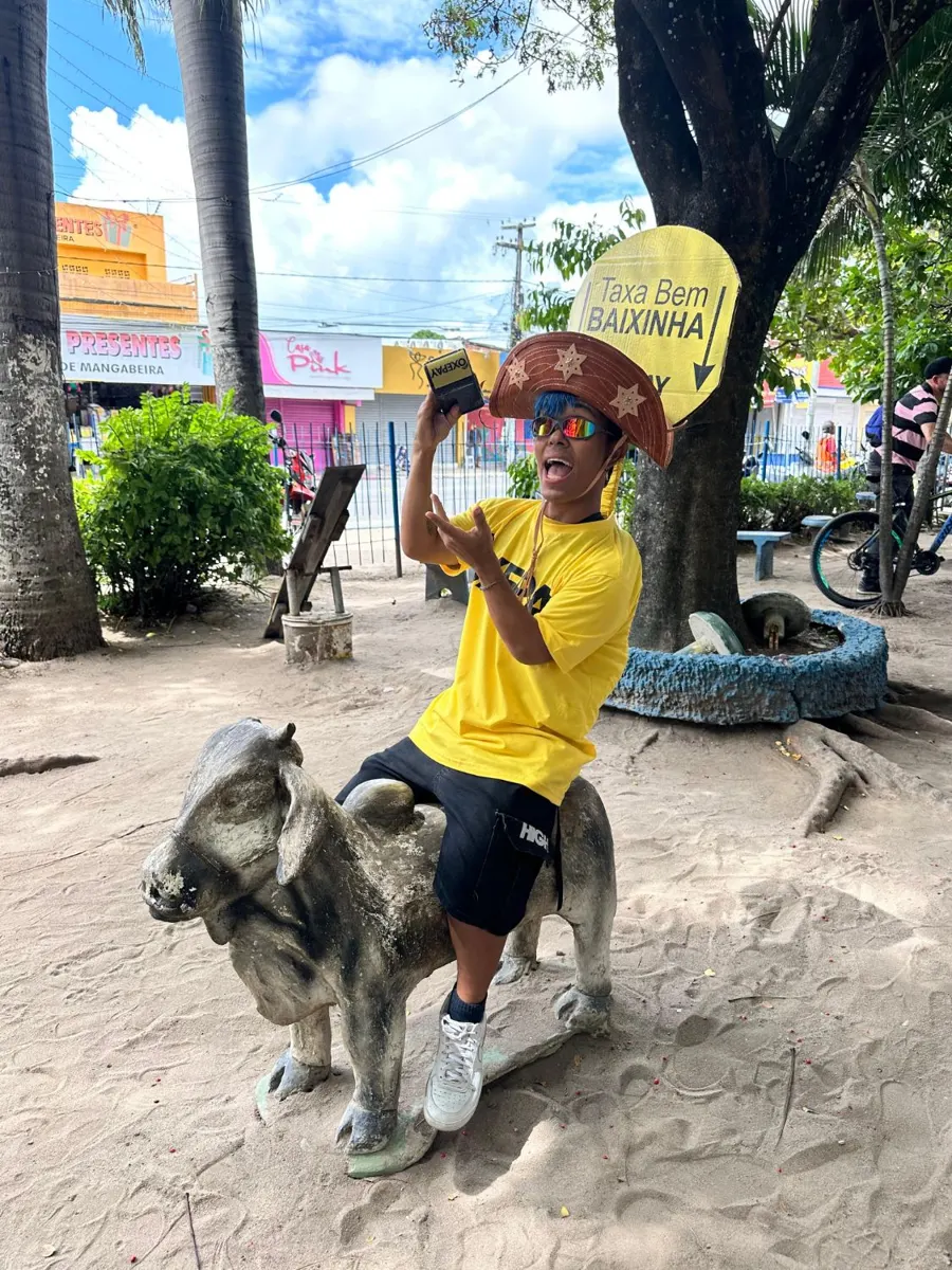 Personagem OxePay montado num bicho de cimento da praça com a placa Taxa Bem Baixinha
